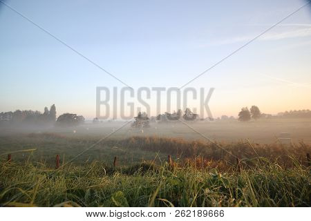Sunrise With Colored Aircraft Trails, Fog On The Meadows And Dyke At River Hollandsche Ijssel In The