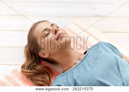 fitness, sport and healthy lifestyle concept - woman doing yoga corpse pose at studio