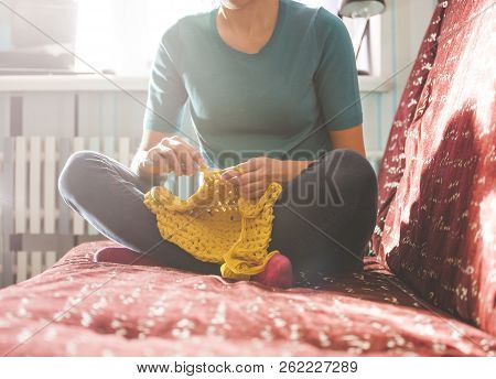 Woman Knits Crochet. The Girl Sits On The Couch And Knits From Knitting Yarn. Crochet Thick Threads.