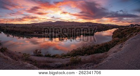 Super Wide Banner Panorama Of A Clorofuls Sunset Reflecting Off The River And The Mountains In The B