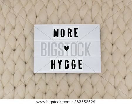 More Hygge Word On Lightbox On Knit Background. Cozy Compozition. Knit Background.