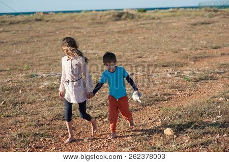 Poor Children Sister And Brother Refugees Walking Through Desert