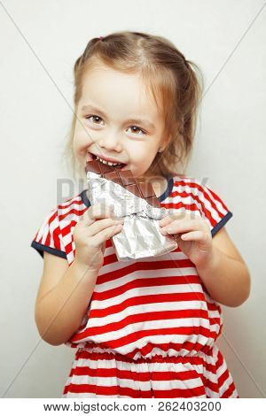 Lady Of Young Age Eating Chocolate Wrapped In Tinfoil