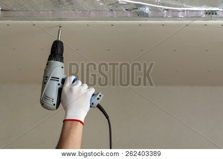 Close-up Of Constructor Worker Hand In Protective Glove With Electrical Cordless Screwdriver Connect