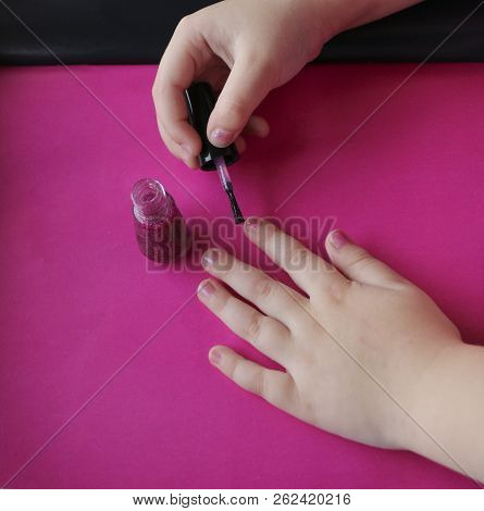 Children's Hands Paint Their Nails With Pink Shiny Nail Polish. Children's Manicure. Glamorous Pink 