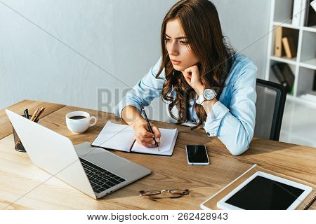 Concentrated Woman At Tabletop With Laptop Taking Part In Webinar In Office