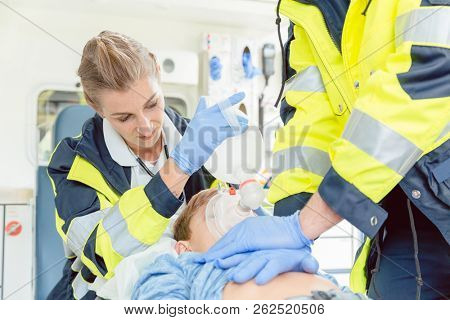Emergency doctor giving cardiac massage for reanimation in ambulance to woman