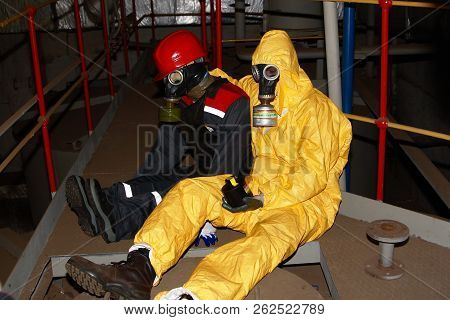 Surgut GRES-2. FIRE-FIGHTING PART -134. Surgut, Russia. 24.07.2012. Rescue exercises at a chemical plant to rescue the victim. Two figures in protective clothing and gas masks depicting victims of chemical poisoning.