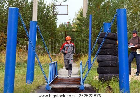 Surgut GRES-2. FIRE-FIGHTING PART #134. Surgut, Russia. 09/11/2014. Competitor runs to the suspension bridge to overcome obstacles. Fire safety. The stages of the competition for firefighters.