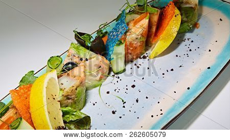 Fried Fish Rolls With Herbs And Vegetables On Blue Plate.