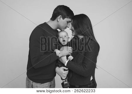 Baby On The Hands Of Parents On A White Background.
