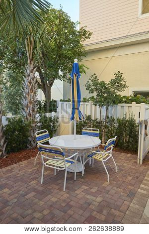 Chairs, Table And Sun Umbrella On Brick Patio