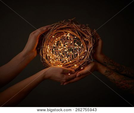 Bright garlands. decorating a wreath of branches in the hands of a woman with a tattoo and men on the black background. Christmas concept