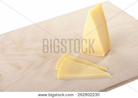 Block Of Cheese With Cut Pieces On A Cutting Board, Isolated On White Background