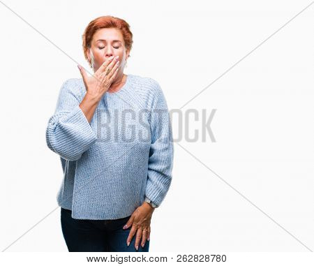 Atrractive senior caucasian redhead woman wearing winter sweater over isolated background bored yawning tired covering mouth with hand. Restless and sleepiness.