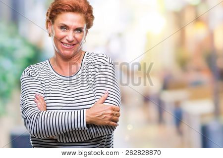 Atrractive senior caucasian redhead woman over isolated background happy face smiling with crossed arms looking at the camera. Positive person.
