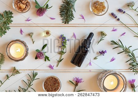 Bottles Of Essential Oil With Frankincense, Hyssop, Lavender And Other Herbs On A White Background