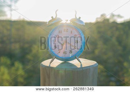 Vintage Blue Alarm Clock On Summer Forest Background. Daylight Saving Time Concept Winter Time