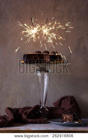 Chocolate Cake On A Gkass Plate Drizzled With Chocolate Sauce And A Lights. Christmas Chocolate Cake