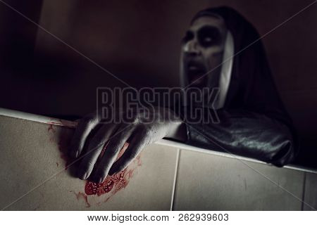 closeup of a frightening evil nun, wearing a typical black and white habit, with her hands stained with blood