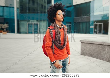 Young Fashionable Dressed Curly Black African American With Glasses Walks Through The Streets Agains