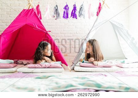 Preteen Girls Talking While Lying In Tipi Tents During Slumber Party At Home