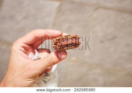Man Hand Holding French Chocolatte Macaron On Gray Background