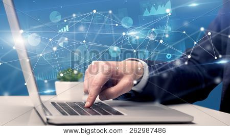 Businessman typing on laptop with linked reports charts grapghs around