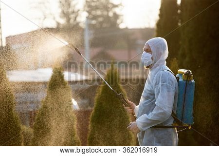 Man in protective equipment decontaminating and spraying on a public place as a prevention against Coronavirus disease 2019, COVID-19. Coronavirus pandemic.