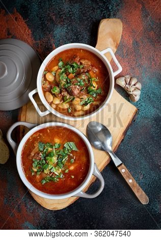 Bean Soup With Meat And Vegetables Served On A Rustic Board With Garlic. Traditional Balkan Soup Or 