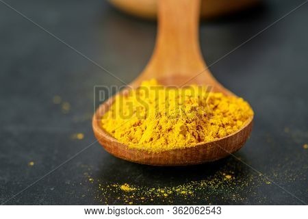 Turmeric Powder In Wooden Spoon Closeup. Healing Spice, Anti-inflammatory Effect, Immunomodulator. H