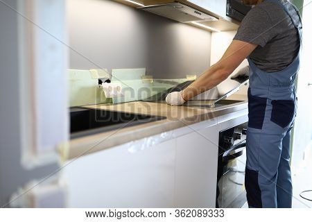 Repairman Installs Hob Kitchen Table In Apartment. Installation Hob In Countertop. Purchase New Kitc