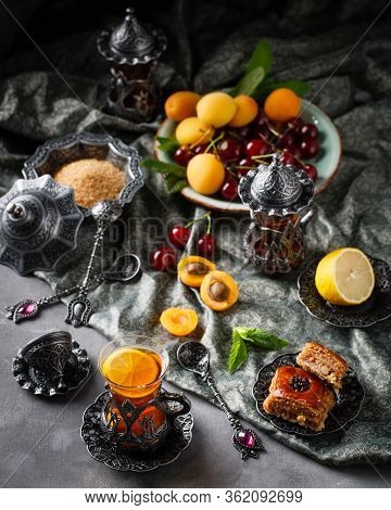 Tea Armud In Turkish Style With Lemon. Served On A Silk Tablecloth With Baklava And Fruit-cherries A