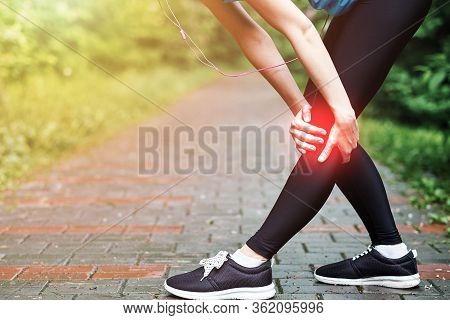 Woman Athlete Runner Touching Knee In Pain, Fitness Woman Running In Summer Park. Healthy Lifestyle