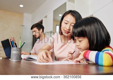 Mother Helping Daughter With Drawing When Father Working On Laptop At Home During Quarantine Time