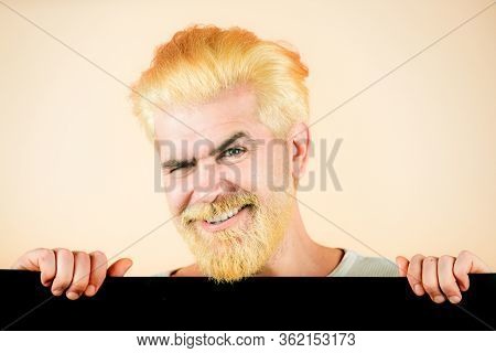 Young Happy Man Shows A Sheet Of Paper In The Camera On A Color Background. Male Model Holding Black