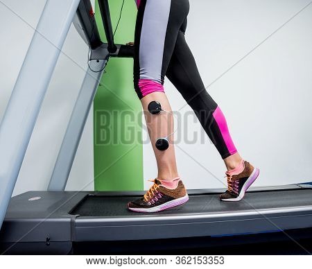Young Sports Woman With Electrostimulator On The Muscles Of The Legs.