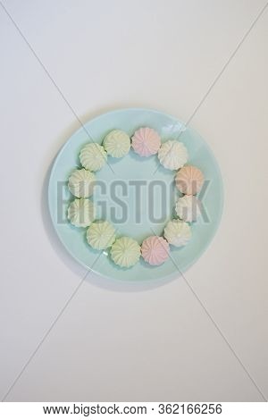 Sweet Paste Colored Bise On A Delicate Blue Plate On A White Table. Good Morning. Flat Lay