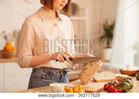 Mid-section Portrait Of Modern Young Woman Cutting Fresh Wholewheat Bread While Making Breakfast In 