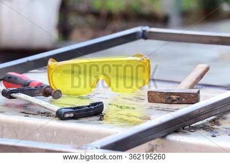 Welding Work. Metal Profile, Safe Glasses, Hammer And Clamp On A Metal Table. Tools For Electro Weld