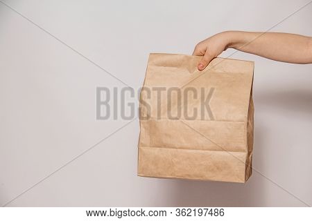 Brown Craft Paper Bag For The Removal Or Delivery Of Goods And Food In Hands On A White Background. 