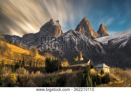 Church In A Village In The French Alps With Mountains 3000 Meters High. First Autumn Snowfall With B
