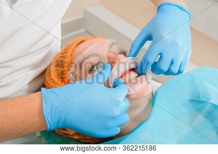 A Young Female Dentist Pulls A Mouth Extender At A Dental Clinic.