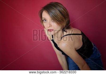 Young Woman With Short Hair Dressed In Black Lace Bustier And Blue Jeans Is Posing In The Studio On 