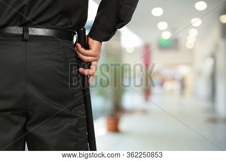 Security Guard In Uniform With Police Baton In Shopping Mall, Closeup. Space For Text