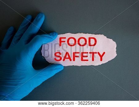 Hand In Blue Glove With White Small Paper. Concept Words Food Safety.