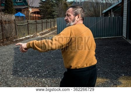 Elderly village man in a sweater on the street