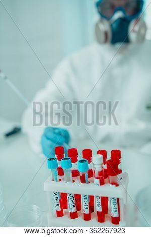 COVID-19. Doctor, microbiologist, scientist in a protective suit, makes a research on blood samples of infected people in the laboratory. Coronavirus test.