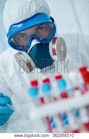 COVID-19. Doctor, microbiologist, scientist in a protective suit, makes a research on blood samples of infected people in the laboratory. Coronavirus test.