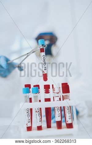 COVID-19. Doctor, microbiologist, scientist in a protective suit, makes a research on blood samples of infected people in the laboratory. Coronavirus test.
